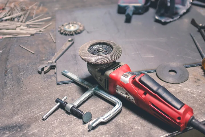 Hand tools and an angle grinder arranged on a workshop bench